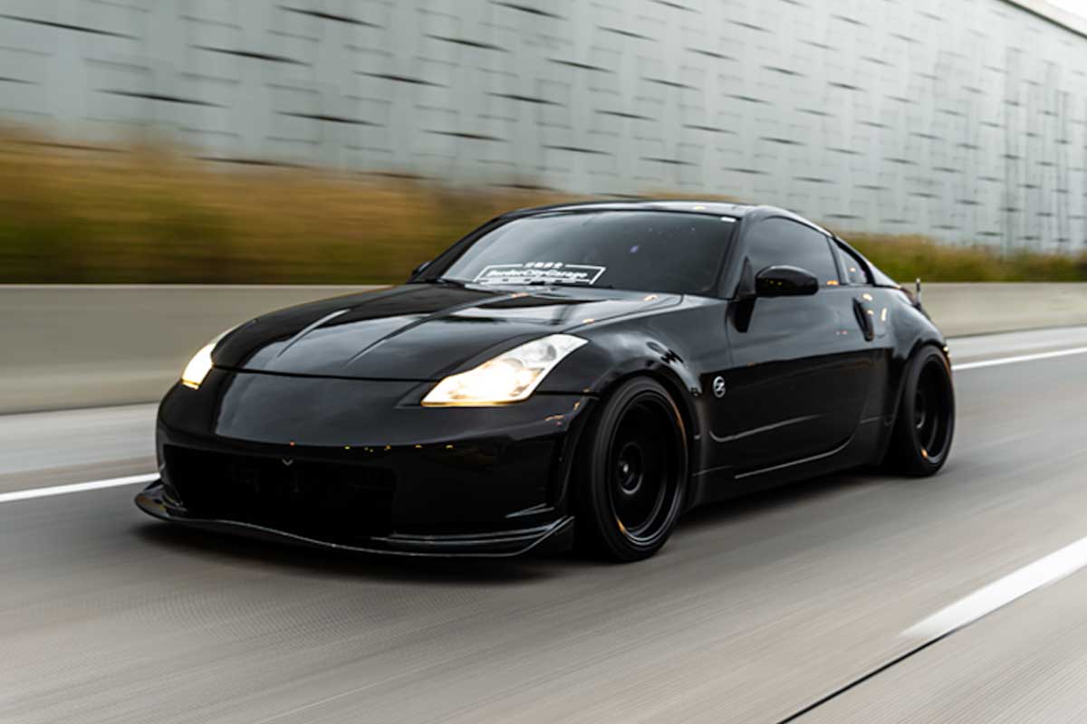 Rolling shot of Michael’s black Nissan 350Z on the highway with aggressive fitment